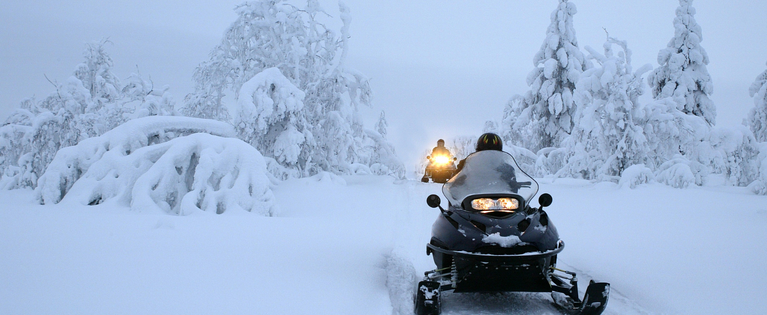 Snowmobiles in snowy mountain trails.